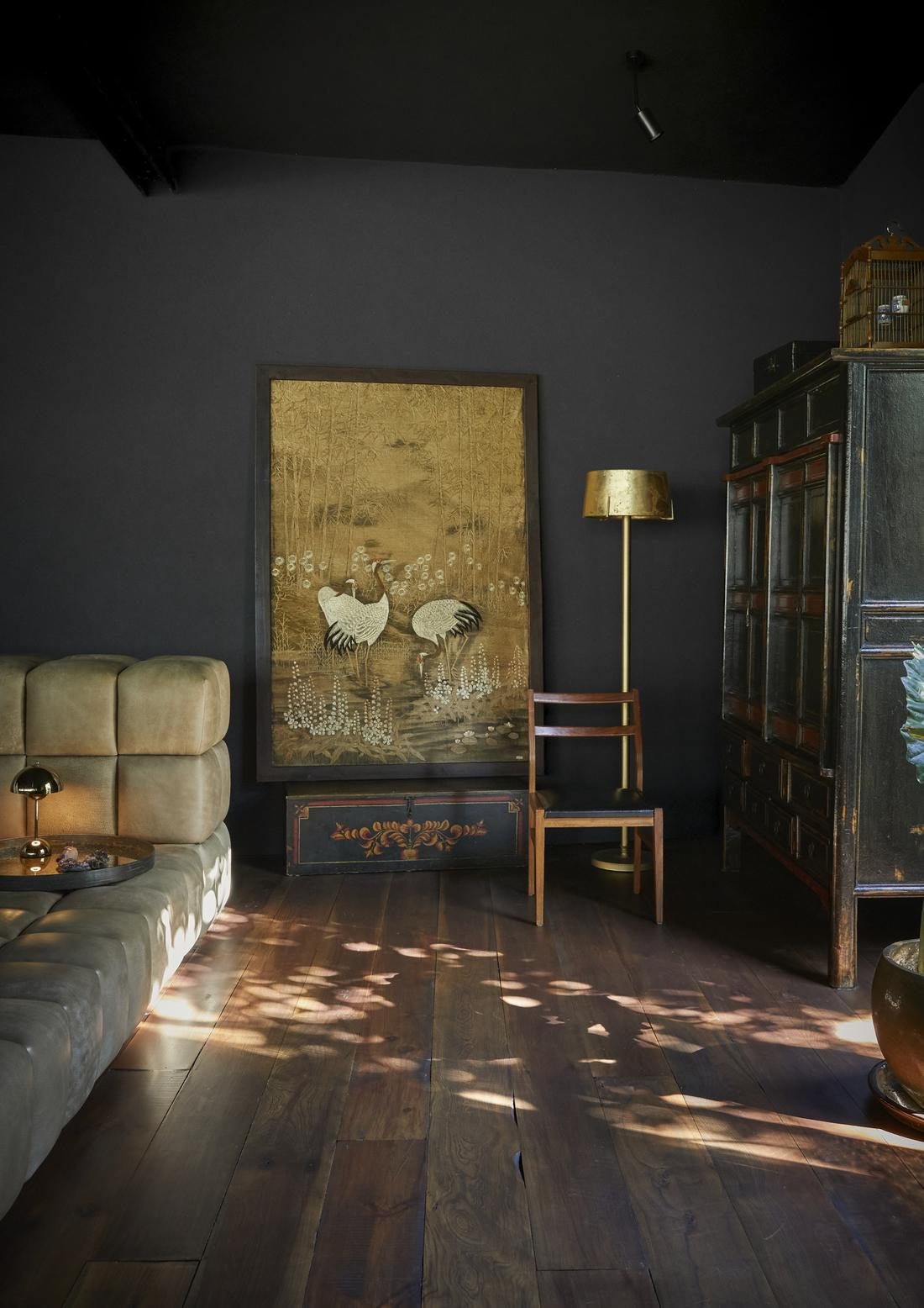 Embroidered crane artwork, a brass floor lamp and an antique cabinet