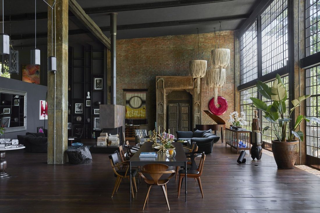 Open plan living area with a brick wall, fringed chandeliers and floor to ceiling windows