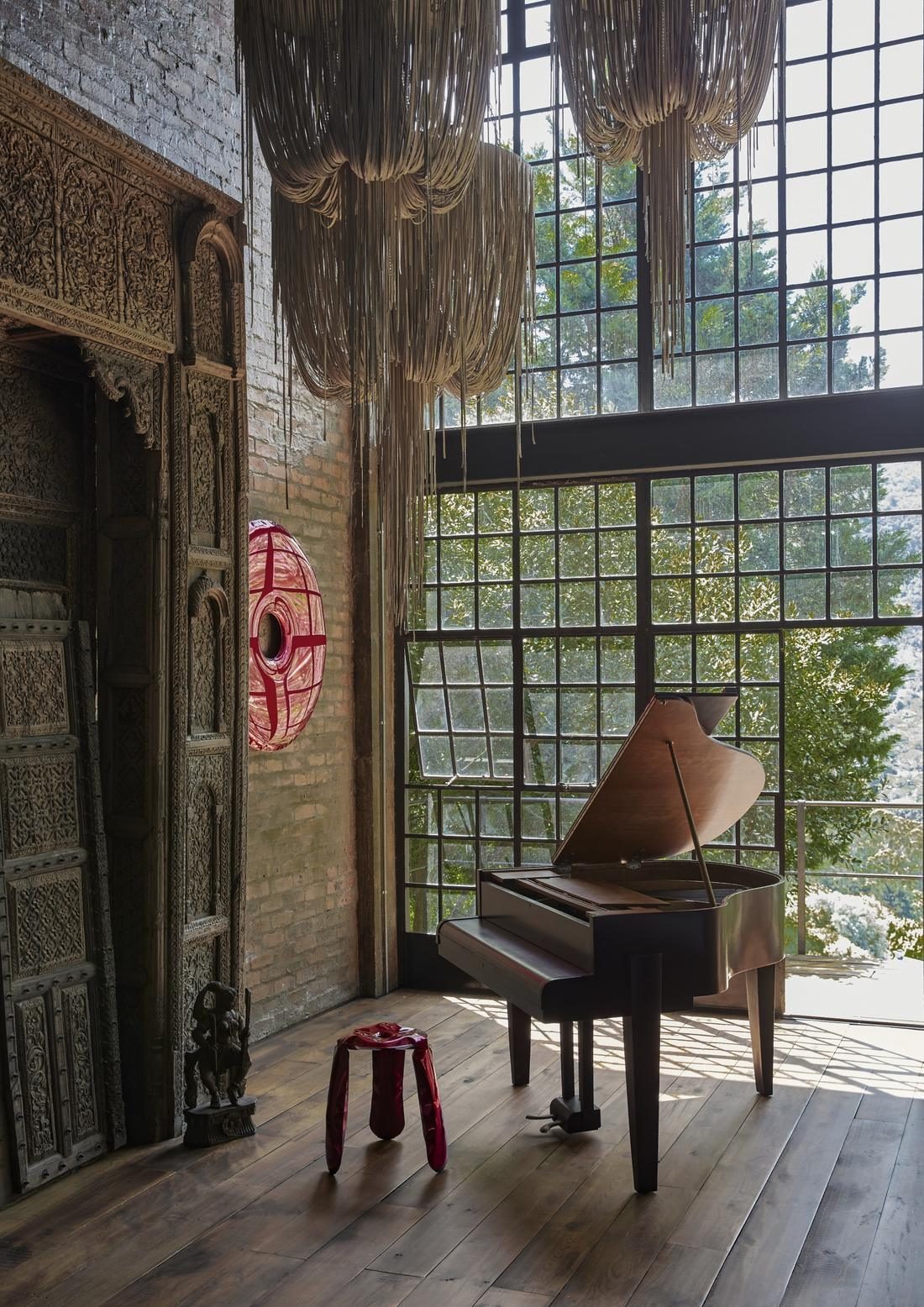 Grand piano beside a carved timber doorway and tall steel framed windows