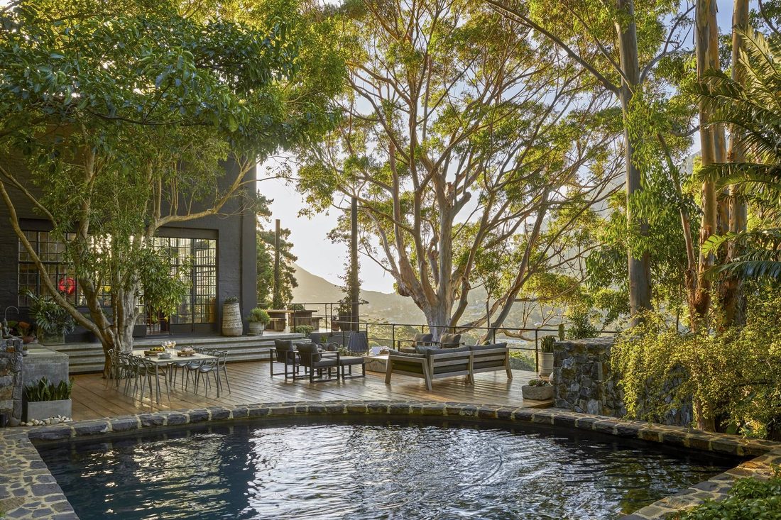 Dark stone edged pool reflecting the surrounding trees, with the timber deck beyond